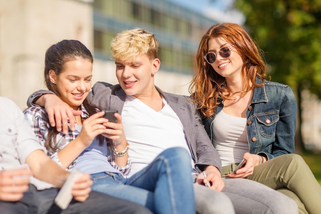 vacaciones de verano, educación, campus, tecnología y concepto adolescente - grupo de estudiantes o adolescentes con teléfonos móviles