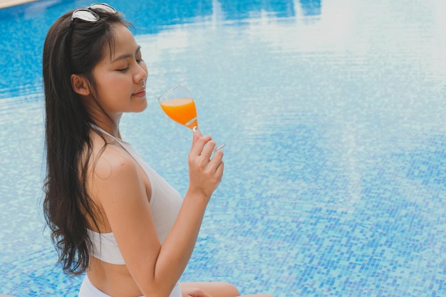 Vacaciones de verano Joven asiática Hermosa mujer relajante en la piscina en el balneario Hermosa playa tropical frente al hotel resort con piscina