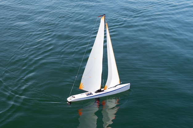 Vacaciones de verano. Libertad de navegación. un yate de juguete navega en el mar. Barco de juguete de vela en la superficie del mar. Navegación y vela. Modelo de nave.