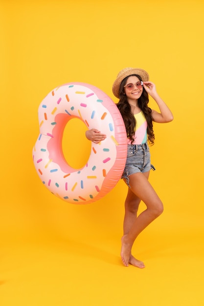 Vacaciones de verano. niña feliz con sombrero de paja y gafas de sol anillo de donut inflable. Accesorio de playa para niños con anillo de natación circular inflable. infancia activa. fin de semana de verano para niños. bronceado.