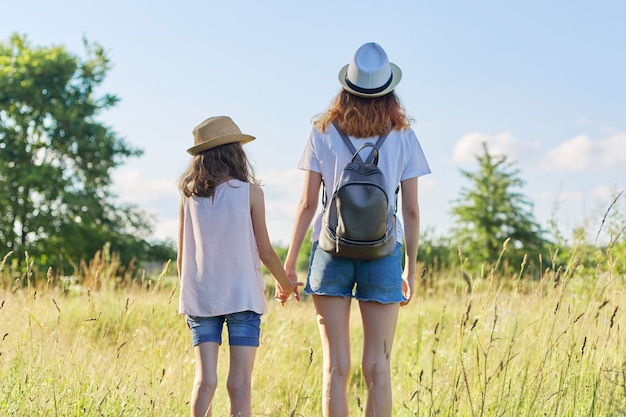 Vacaciones de verano, niños dos hermanas caminando juntos tomados de la mano