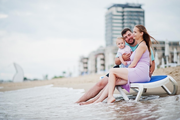 Vacaciones de verano Padres y personas actividad al aire libre con niños Felices vacaciones en familia Padre madre embarazada hija sentada en la tumbona en la playa de arena de mar