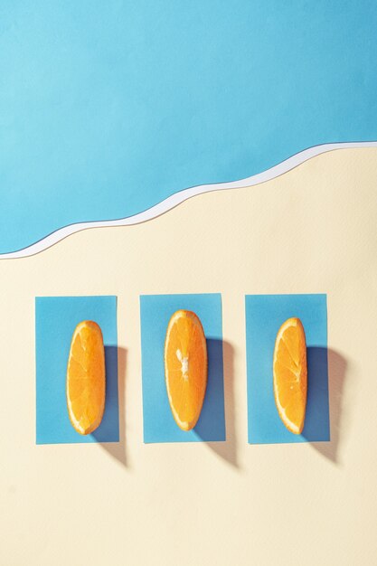 Vacaciones de verano en la playa cerca del mar azul - Las naranjas se acuestan sobre las toallas y toman el sol - Lay Flat