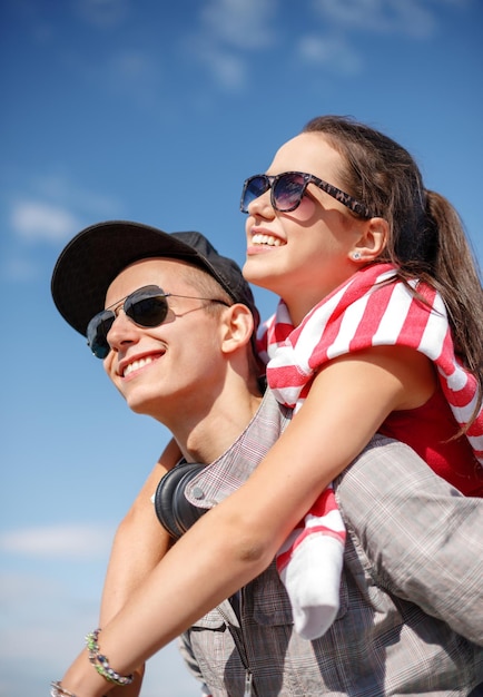 vacaciones de verano, relaciones y concepto adolescente - adolescentes sonrientes con gafas de sol divirtiéndose afuera