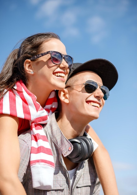 vacaciones de verano, relaciones y concepto adolescente - adolescentes sonrientes con gafas de sol divirtiéndose afuera