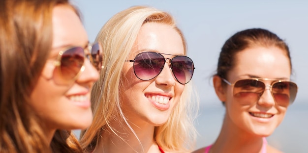 vacaciones de verano, vacaciones, amistad y concepto de la gente - cerca de mujeres jóvenes sonrientes con gafas de sol