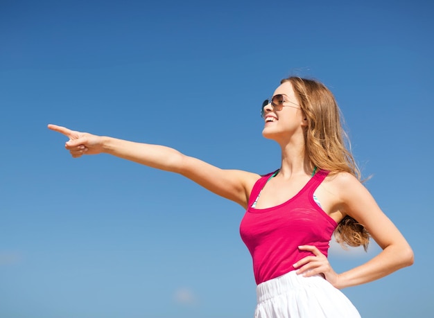 vacaciones de verano y vacaciones - chica mostrando la dirección en la playa