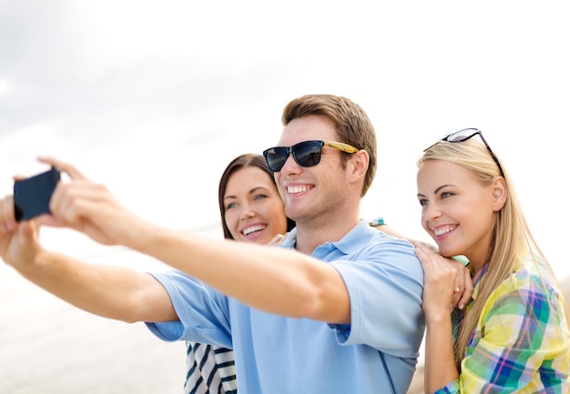 vacaciones de verano, vacaciones, concepto de gente feliz - grupo de amigos tomando selfie con teléfono celular en la playa