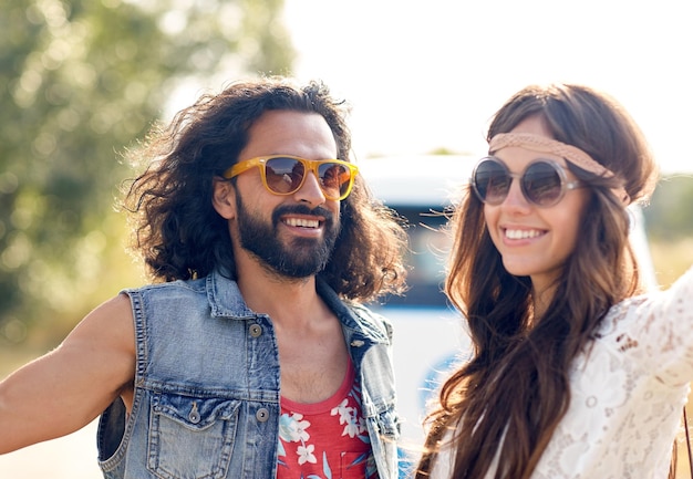 vacaciones de verano, viaje por carretera, vacaciones, viajes y concepto de la gente - sonriente joven pareja hippie sobre camión monovolumen