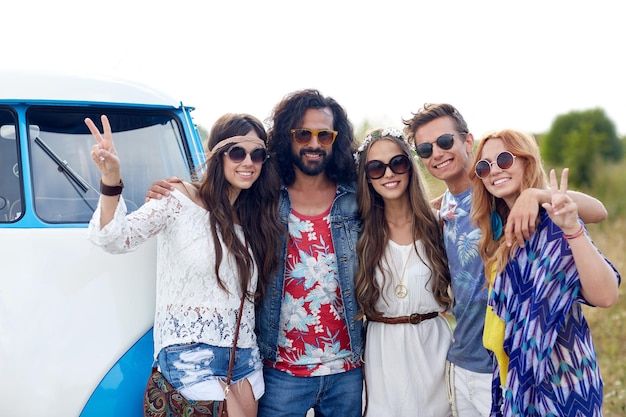 Foto vacaciones de verano, viaje por carretera, vacaciones, viajes y concepto de personas - jóvenes amigos hippies sonrientes sobre un camión monovolumen
