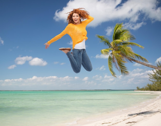 vacaciones de verano, viajes, turismo, libertad y concepto de personas - mujer joven sonriente saltando en el aire sobre fondo de playa tropical