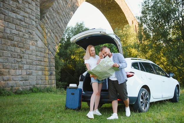 Vacaciones, viajes: la familia está lista para viajar durante las vacaciones de verano. ruta de maletas y coche. Personas con mapa en manos planeando viaje por carretera. concepto de viaje. viajero.