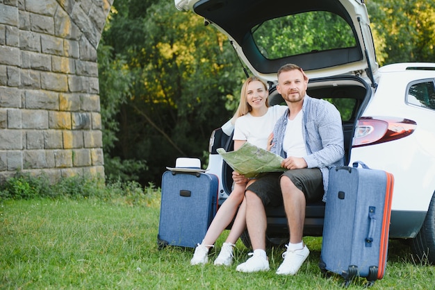 Vacaciones, viajes: la familia está lista para viajar durante las vacaciones de verano. ruta de maletas y coche. Personas con mapa en manos planeando viaje por carretera. concepto de viaje. viajero.