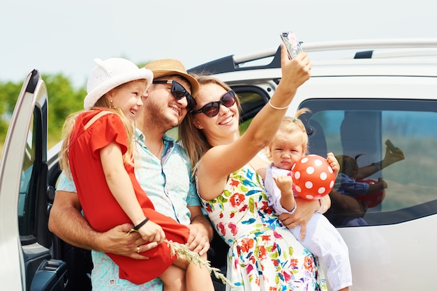 Vacaciones, viajes: familia feliz lista para viajar a las vacaciones de verano. La gente se divierte y toma fotos por teléfono. Tómate una selfie en el recuerdo del viaje