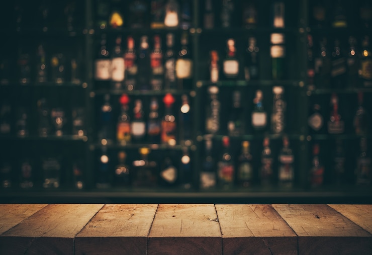 Foto vacía la parte superior de la mesa de madera con la barra de contador borrosa y las botellas