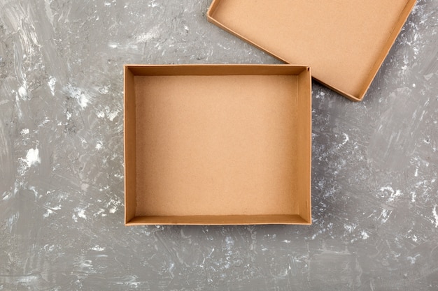 Vaciar la caja de cartón marrón abierta para maqueta en la mesa de cemento gris con espacio de copia