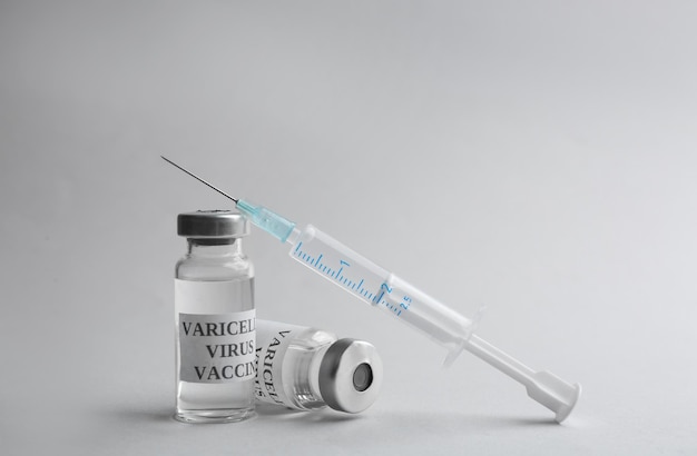 Vacina contra varicela e seringa em fundo cinza claro Prevenção do vírus varicela