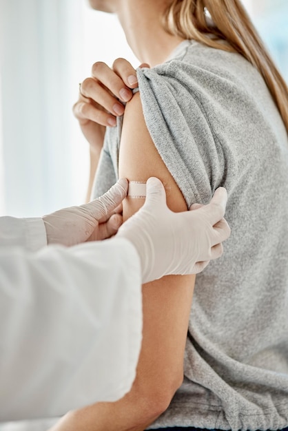 Vacina Covid e médico aplicando gesso ao paciente após receber tratamento médico durante a pandemia Fechamento do profissional de saúde colocando adesivo médico após consultar uma mulher no hospital