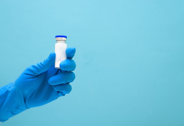 Vacina de vírus na mão em uma luva azul médica contra o coronavírus. terapia clínica da epidemia. cuidando da saúde das pessoas