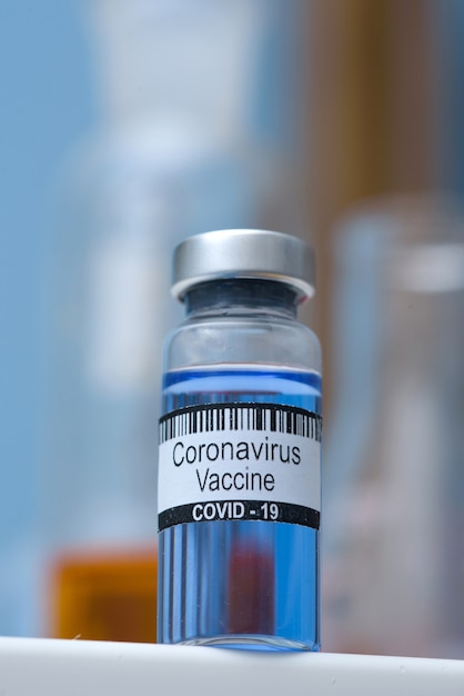 Vacina do coronavírus em frasco para injeção na mesa contra o laboratório médico de fundo, espaço para texto. Derrotando a epidemia de coronavírus SARS-CoV-2.