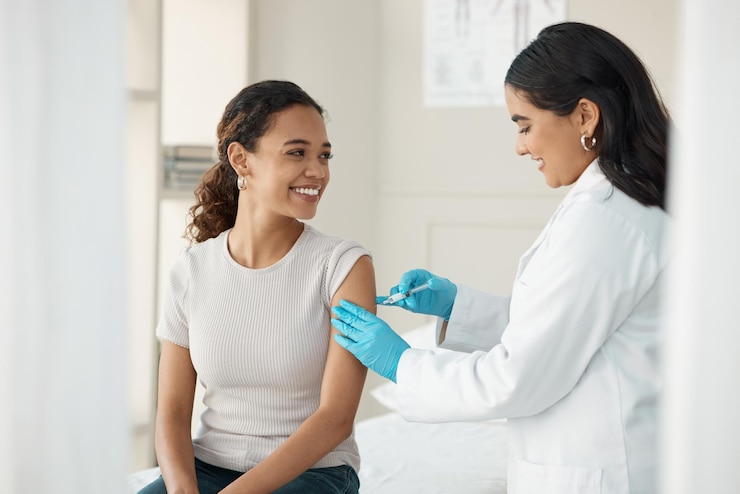 Foto vacina injetável e paciente na clínica para consulta e ajuda na prevenção com um sorriso médico injeta e mulher no braço para vírus com luvas na sala médica para bem-estar ou saúde