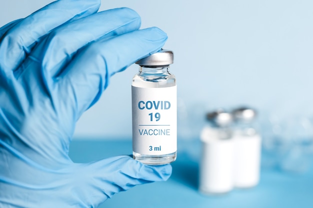 Vacina para o coronavírus. A mão do médico em um tubo segurando uma luva médica com a vacina do Coronavirus para o vírus COVID 2019-nCoV. Conceito do Coronavirus 2019. Nova cepa