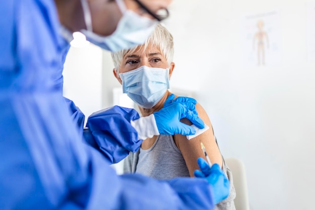 Vacinação Covid-19. Paciente sênior sendo vacinado contra o coronavírus recebendo injeção intramuscular da vacina Covid durante a consulta médica no hospital. Imunização com vírus corona