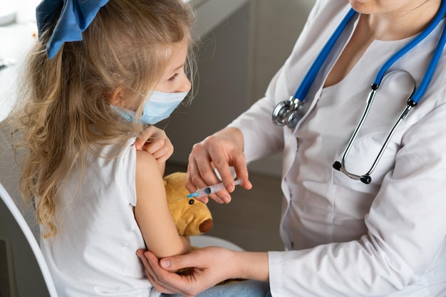 Vacinação de crianças uma menina em uma consulta médica uma injeção no braço a concepção