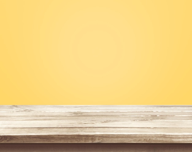 Vacío de mesa de madera sobre fondo de color amarillo pastel.
