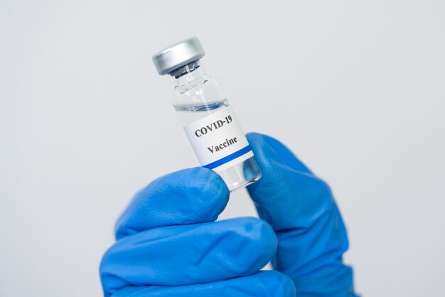 Foto vacuna contra el coronavirus botella de covid-19 para inyección en la mano de un médico o técnico científico en un traje de protección cuidado de la salud antiviral y médico concepto de peligro biológico