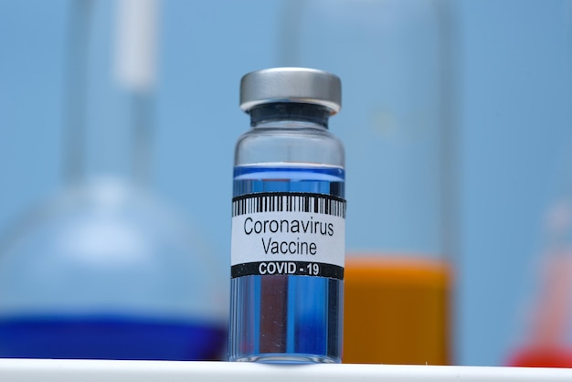 Vacuna contra el coronavirus en botella para inyección en la mesa contra el laboratorio médico de fondo, espacio para texto. Derrotando la epidemia de coronavirus SARS-CoV-2.