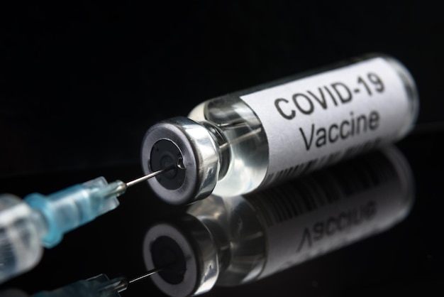 Vacuna contra el coronavirus COVID19 en jeringa negra y cierre de botella