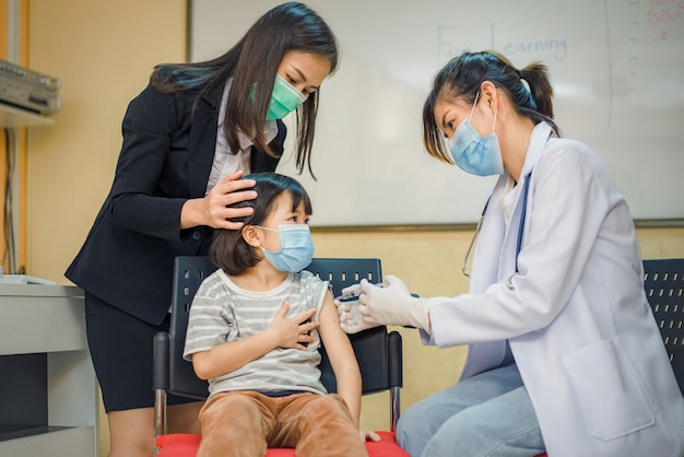 Vacuna contra coronavirus. Vacuna para el COVID-19. Médico que vacuna a los escolares en la escuela para prevenir una grave epidemia entre los escolares. Niño recibiendo la vacuna contra la gripe. Prevención del virus.