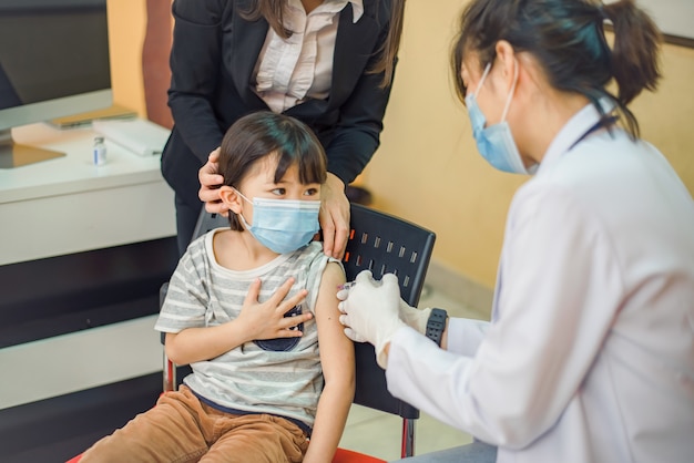 Vacuna contra coronavirus. Vacuna para el COVID-19. Médico que vacuna a los escolares en la escuela para prevenir una grave epidemia entre los escolares. Niño recibiendo la vacuna contra la gripe. Prevención del virus.