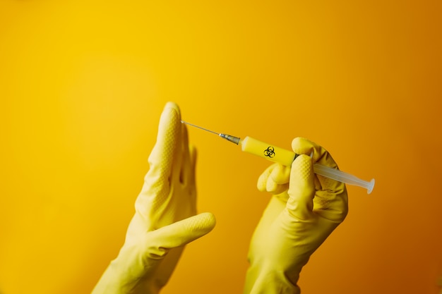 Vacuna de coronavirus en jeringa amarilla, científico en guantes sostiene jeringa, curando para curar covid-19.