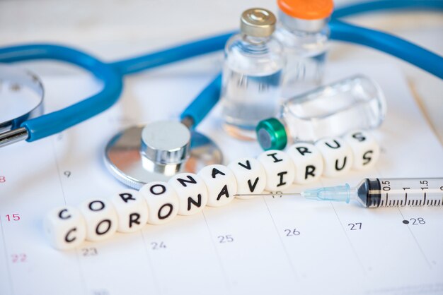 Vacuna de coronavirus con medicamento de inyección de jeringa medicamento y estetoscopio en calendario