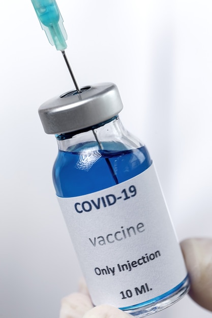 Vacuna COVID-19 en manos del investigador, doctora irreconocible sostiene una jeringa y un frasco con vacuna para curar el coronavirus.