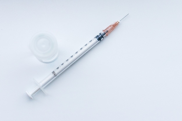 Vacuna en un frasco vial y jeringa de inyección sobre una mesa blanca
