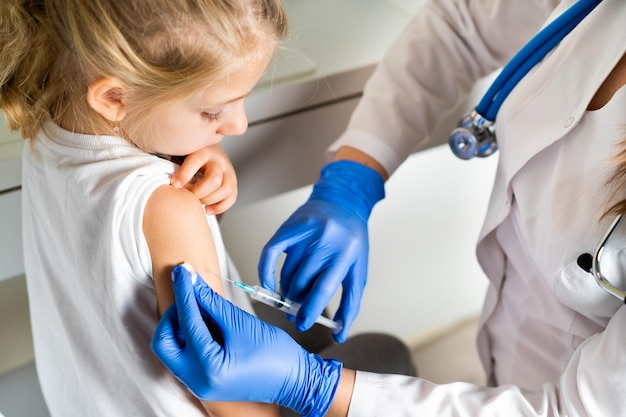 Foto vacunación de niños una niña en una cita con el médico una inyección en el brazo el conce