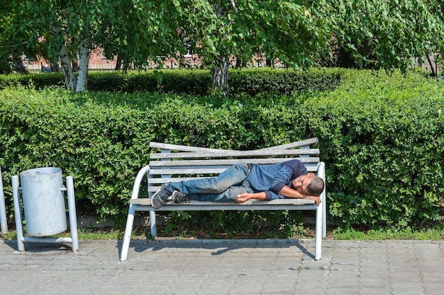 un vagabundo duerme en un banco en un parque