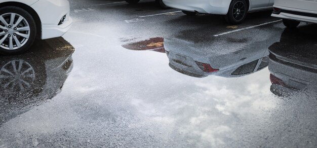 Vagas de estacionamento molhadas após a queda de chuva forte com reflexo do carro na poça no chão. Foco seletivo.