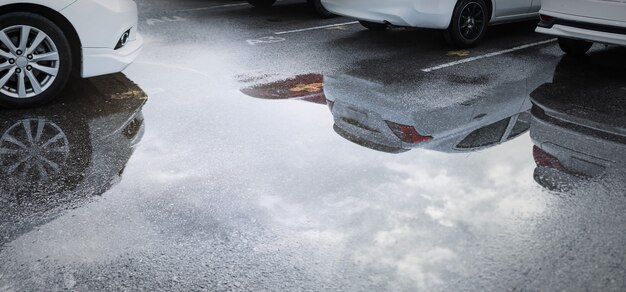 Vagas de estacionamento molhadas após a queda de chuva forte com reflexo do carro na poça no chão. foco seletivo.