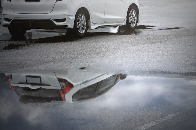 Vagas de estacionamento molhadas após chuva forte caem com reflexo do céu em uma poça no chão. Foco seletivo.