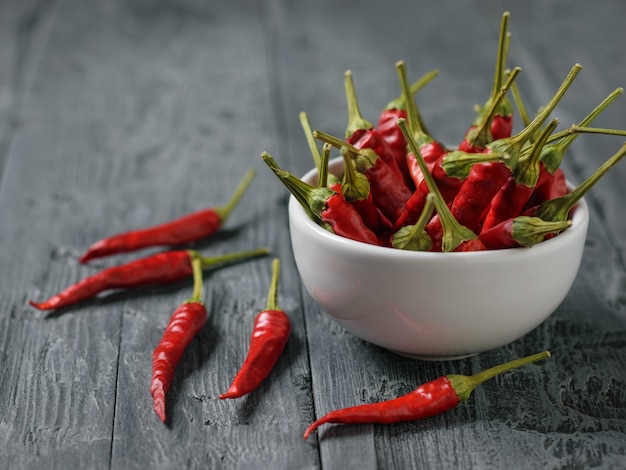 Vagens de pimenta em uma tigela branca sobre uma mesa de madeira preta.