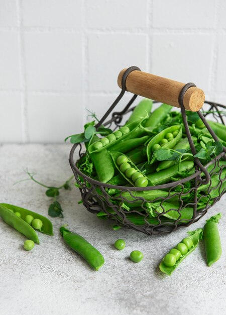 Vainas de guisantes verdes frescos y guisantes con brotes sobre fondo de hormigón