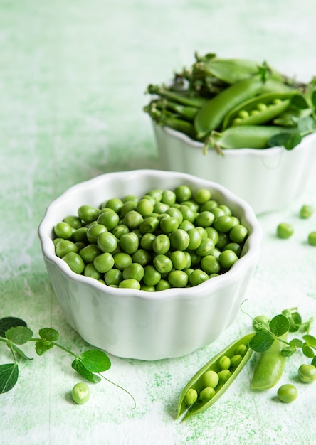 Vainas de guisantes verdes frescos y guisantes con brotes sobre fondo de madera verde. Concepto de alimentación saludable, verduras frescas.