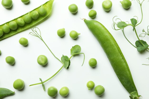 Vainas de guisantes verdes, semillas y ramitas en blanco