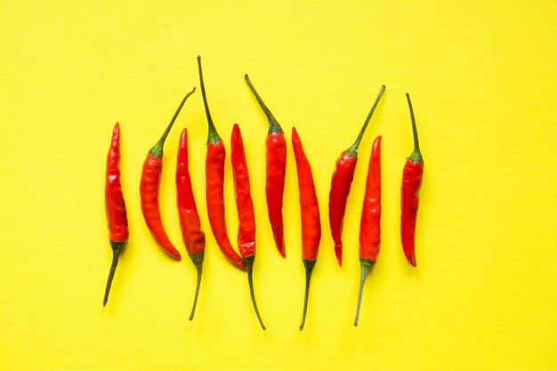 Vainas de pimiento rojo sobre fondo amarillo brillante