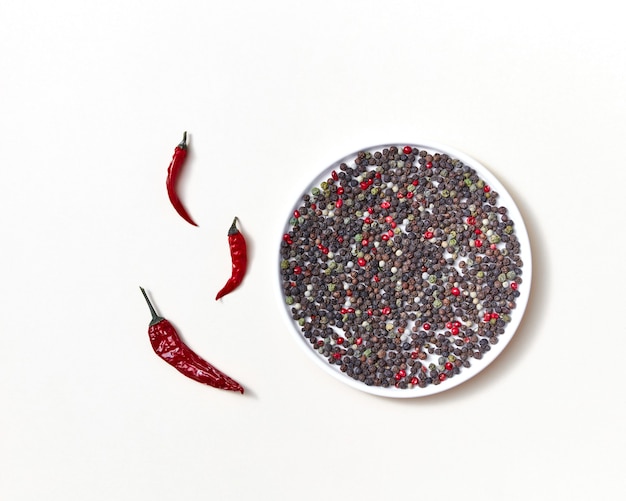 Vainas de tubo rojo de chiles rojos con una mezcla de diferentes tipos de pimiento en una placa blanca sobre un fondo blanco.