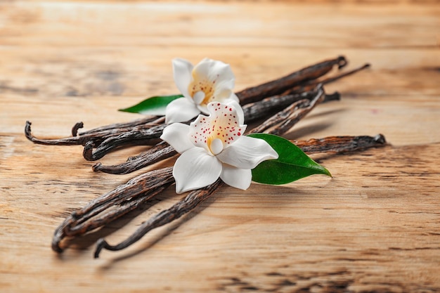 Vainas de vainilla secas y flores sobre fondo de madera